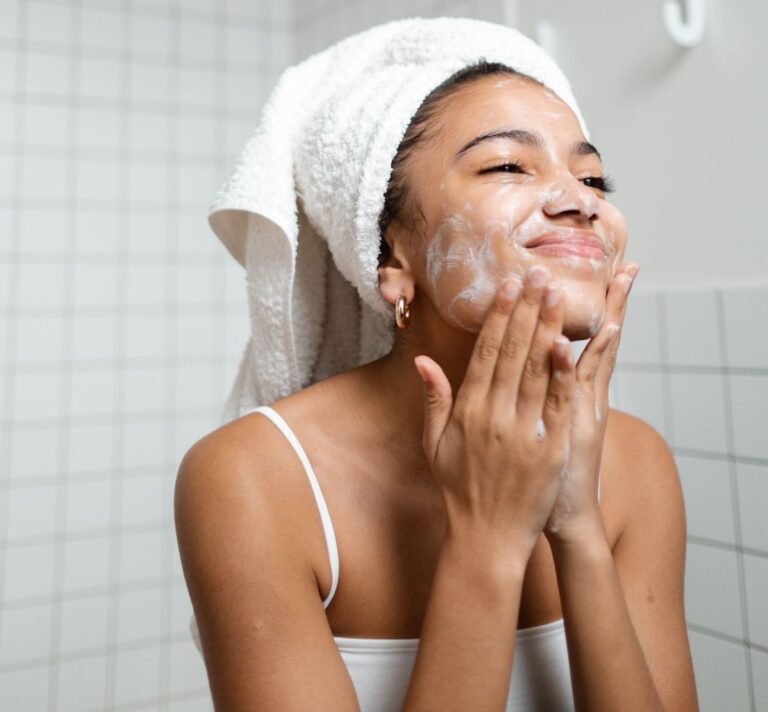 A young woman enjoying her skincare routine with a towel wrapped, indoors.