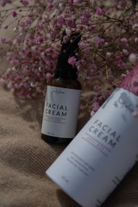 Close-up of anti-age facial cream bottles with delicate pink blossoms in a studio shot.