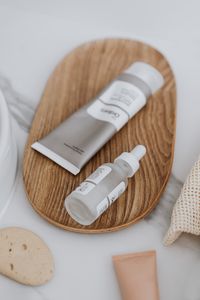 Minimalist display of skincare products including a serum and cream on a wooden tray, promoting eco-friendly beauty.