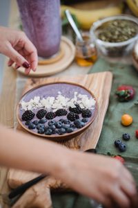 Vibrant berry smoothie bowl being prepared with fresh fruits and toppings.